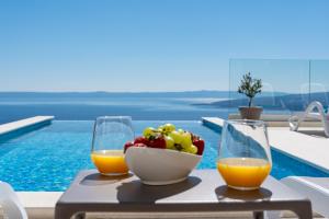 a table with two glasses of orange juice and a bowl of fruit at Villa Bellevue Bast in Baška Voda