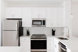 a white kitchen with a stove and a microwave at Kasa Southside Jacksonville in Jacksonville