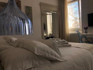 uma cama branca com almofadas e um vaso em cima em B&B Dimor'à em Pitigliano