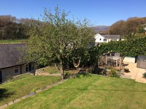 a yard with a tree and a house at Lovely cottage in Snowdonia, private hot tub, by mountains & award winning beach in Fairbourne