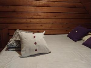 a bed with a white pillow and some pillows at La Cabaña in Tandil