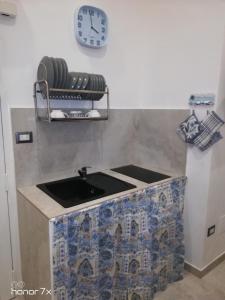 a kitchen with a sink and a clock on the wall at Maison de Marie in Trani