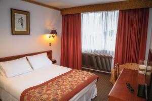 Habitación de hotel con cama y ventana en HOTEL LOS NAVEGANTES en Punta Arenas