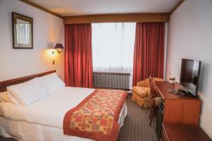 Habitación de hotel con cama, escritorio y TV. en HOTEL LOS NAVEGANTES, en Punta Arenas