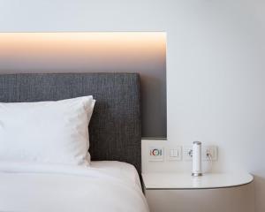 un letto con cuscino bianco e un tavolo con lampada di Mirada Hotel ad Atene