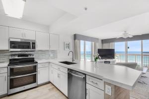 une cuisine avec des armoires blanches et des appareils en acier inoxydable dans l'établissement Pelican Beach Resort 501, à Destin