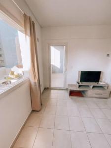 Cette grande chambre blanche dispose d'une fenêtre et d'une télévision. dans l'établissement Espectacular departamento a metros del mar, à Puerto Madryn