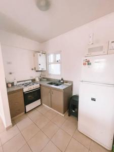 Il comprend une cuisine équipée d'un réfrigérateur blanc et d'une cuisinière. dans l'établissement Espectacular departamento a metros del mar, à Puerto Madryn