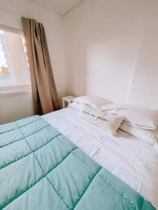 - un lit blanc et bleu dans une chambre avec fenêtre dans l'établissement Espectacular departamento a metros del mar, à Puerto Madryn