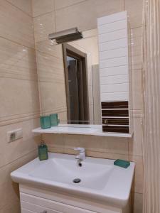 La salle de bains est pourvue d'un lavabo blanc et d'un miroir. dans l'établissement Шикарні апартаменти поруч з Майданом, à Kiev