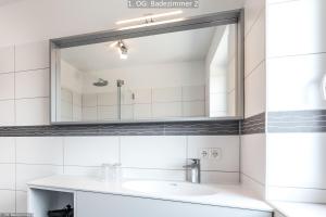 ein Bad mit einem Waschbecken und einem Spiegel in der Unterkunft Marina 22C in Cuxhaven