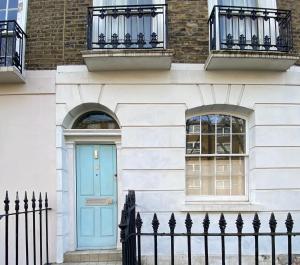une porte bleue sur un bâtiment blanc avec une clôture dans l'établissement The blue door, à Londres