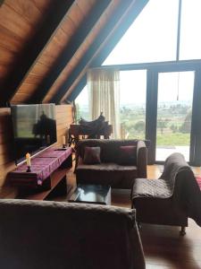 a living room with couches and a tv and a piano at Alpina Glamping en Latacunga in Saquisilí