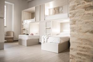 2 łóżka w sypialni z białymi meblami w obiekcie room00 Salvador Hostel w Sewilli