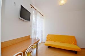 a living room with a yellow bench and a tv on the wall at Apartments Josko in Gradac