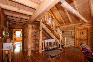Cabaña de madera con escalera en la sala de estar en Beautiful River-Front Log Cabin Near Williamsburg en Toano