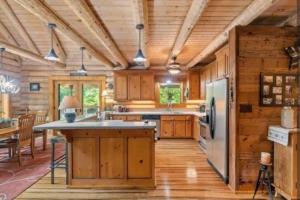 cocina con armarios de madera y nevera en Beautiful River-Front Log Cabin Near Williamsburg en Toano