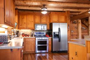 cocina con armarios de madera y nevera de acero inoxidable en Beautiful River-Front Log Cabin Near Williamsburg en Toano