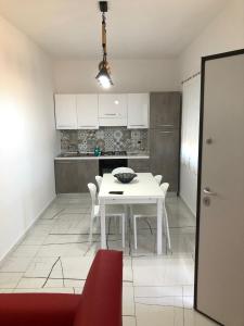 een witte keuken met een witte tafel en stoelen bij Casa vacanze Capo Rizzuto 3 in Ovile la Marinella