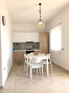 eine Küche mit einem weißen Tisch und weißen Stühlen in der Unterkunft Casa vacanze Capo Rizzuto 1 in Ovile la Marinella