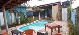 a pool with a table and chairs next to a house at Espaço Alto da Colina em Penedo RJ in Itatiaia