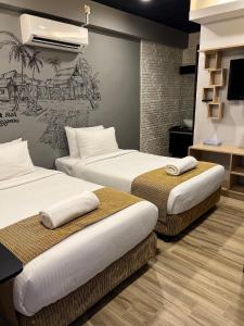 a room with two beds and a wall with a painting at Kuala Terengganu Golf Resort by Ancasa Hotels & Resorts in Kuala Terengganu