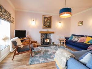 a living room with a blue couch and a fireplace at 2 Pant Y Celyn in Caernarfon