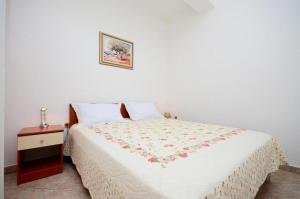 a bedroom with a bed and a nightstand with a white bedspread at Apartments Bovarovic in Pula