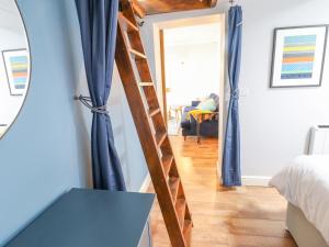 a bedroom with blue curtains and a wooden ladder at 2 Pant Y Celyn in Caernarfon