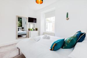 uma cama branca com almofadas azuis e um espelho em Orla-Mo Victorian Captains House,St Ives,Cornwall,Sleeps10-15,Parking4cars,Refurb2022 em St. Ives