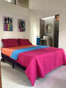 a bedroom with a large bed with red and blue sheets at Villa Wolaba in Puerto Viejo