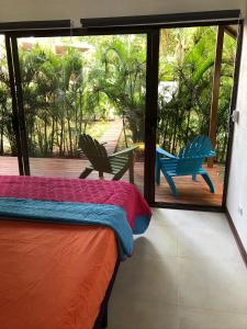 a bedroom with a bed and two chairs on a porch at Villa Wolaba in Puerto Viejo