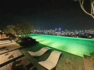 una piscina con 2 sillas blancas por la noche en Beacon Executive Suites - Penang en George Town