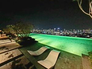 een zwembad met 2 witte stoelen 's nachts bij Beacon Executive Suites - Penang in George Town