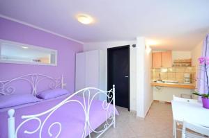 een paarse slaapkamer met een bed en een keuken bij Apartments Ivan Marina in Krk