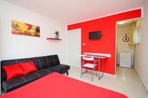 a living room with a couch and a red wall at Apartments Ivan Marina in Krk