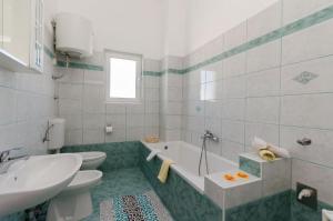 łazienka z wanną, toaletą i umywalką w obiekcie Apartments Krunoslav w mieście Punat