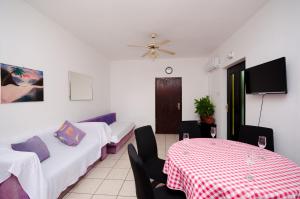 a room with two beds and a table and a ceiling fan at Apartments Petra in Crikvenica