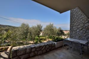 a patio with a table and chairs on a stone wall at Apartments Marija in Cres
