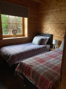 - une chambre avec 2 lits et une fenêtre dans l'établissement Red Squirrel log cabin with hot tub, à Keith