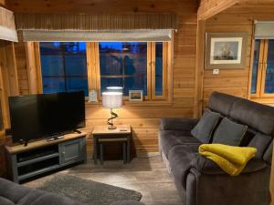 a living room with a couch and a flat screen tv at Red Squirrel log cabin with hot tub in Keith