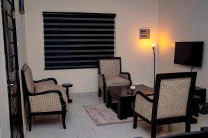 un salon avec trois chaises, une table et une télévision dans l'établissement RESIDENCES AMADIRA, à Parakou