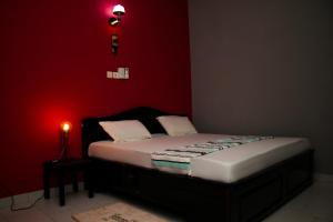 Ce lit se trouve dans une chambre dotée d'un mur rouge. dans l'établissement RESIDENCES AMADIRA, à Parakou