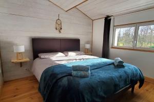 1 dormitorio con 1 cama grande con manta azul en Gîte Rouge Safran pour 4 personnes, en Marsac-en-Livradois