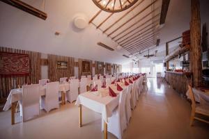 a dining room with white tables and chairs and a clock at Lamminmäen Juhla ja Peti in Joutsa