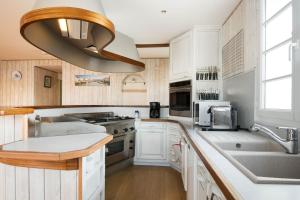 una cucina con armadi bianchi, lavandino e aandelier di Acacias belle maison avec Piscine chauffée, Spa et Sauna a Rivedoux-Plage