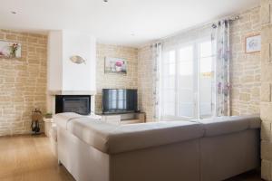 un soggiorno con divano e TV di Acacias belle maison avec Piscine chauffée, Spa et Sauna a Rivedoux-Plage