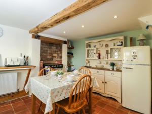 uma cozinha com uma mesa e um frigorífico branco em Hen's Cottage em Chippenham