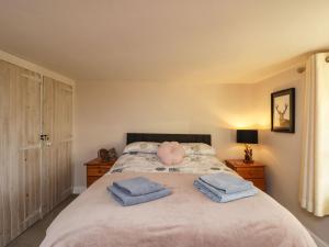 a bedroom with a bed with two towels on it at Hen's Cottage in Chippenham