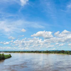 a river under a blue sky with clouds at Hotel Beijing Caucasia in Caucasia